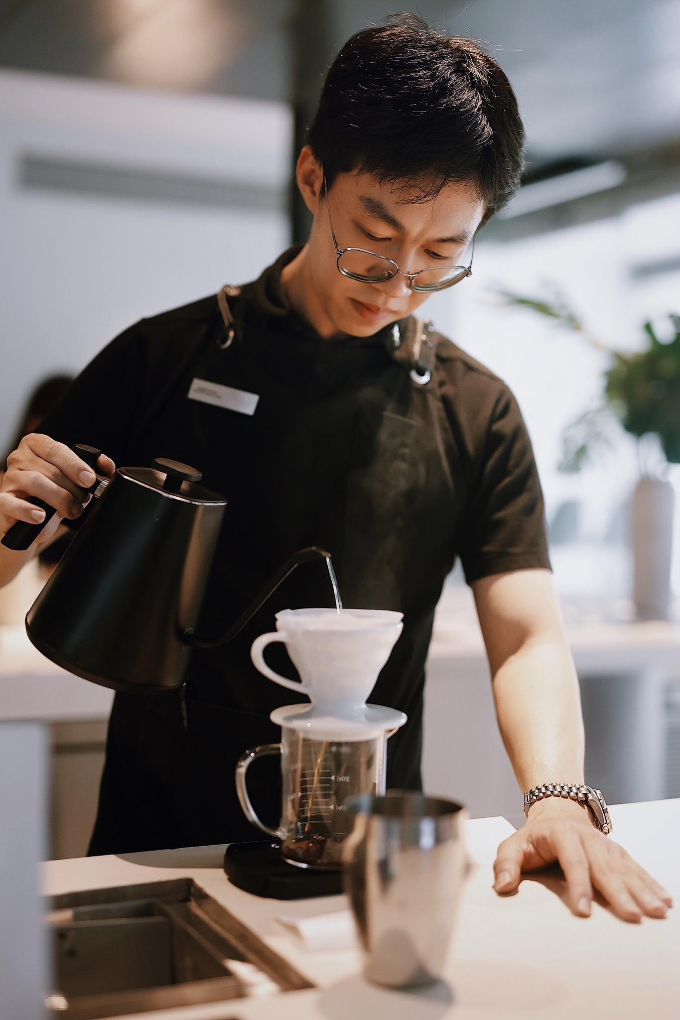 Barista carefully making pour-over coffee.